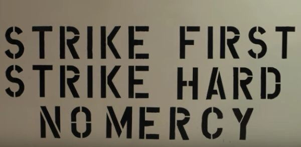 there is a sign that says strike first, strike hard, no merrcy