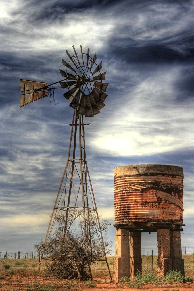 an old rusted water tank next to a windmill