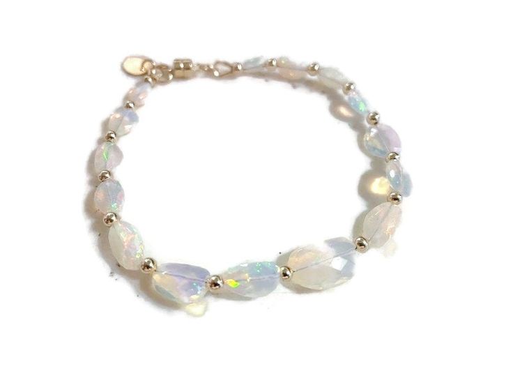 This opal bracelet created by Jewelry by CARMAL is made of nugget natural Ethiopian opal gemstones, 14k gold: beads, and magnetic clasp closure. This bracelet measures 7 1/2 inches in length and is finished with at 14k gold oval charm.  The pictures do not do this bracelet justice! This bracelet would go great with these earrings: https://www.etsy.com/listing/1530862840/ethiopian-opal-earrings-october?click_key=ff8af590c11569fc9ae2a12061e1d30023f83387%3A1530862840&click_sum=89e7b0ab&ga_search_qu Formal Adjustable Iridescent Jewelry, Elegant Crystal Bracelet With Gemstone Beads And Moonstone, Elegant White Faceted Beaded Bracelets, Elegant White Beaded Bracelets With Gemstones, Elegant White Gemstone Beaded Bracelets, Elegant White Beaded Gemstone Bracelets, Elegant Handmade White Gemstones, Elegant Opal Jewelry With Gemstone Beads, Elegant White Faceted Bracelets