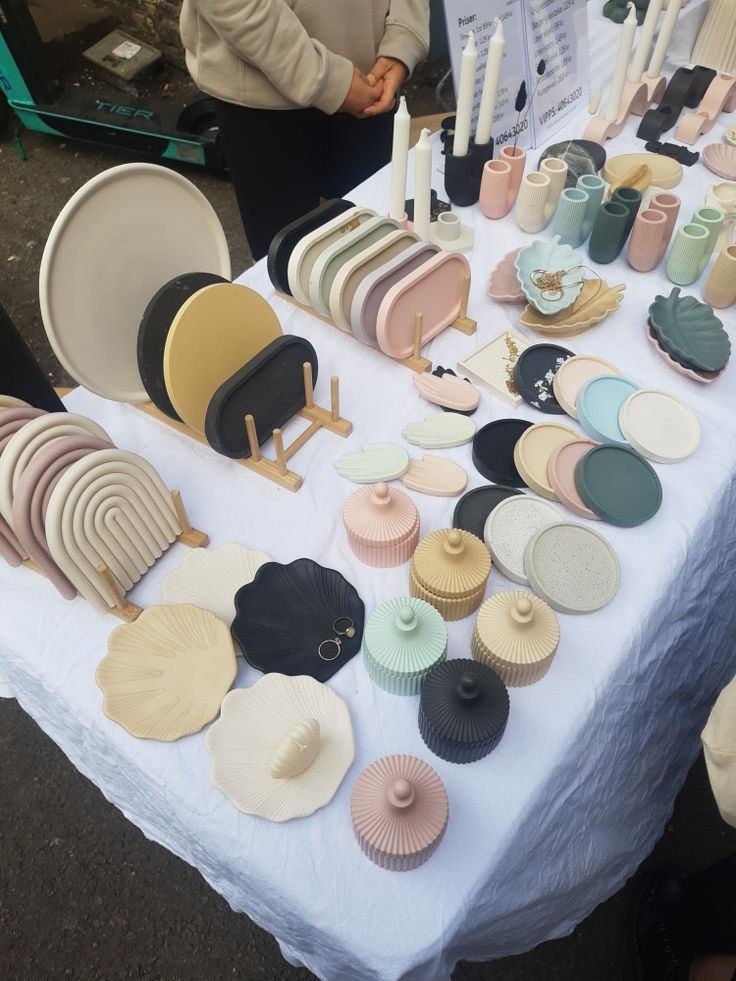 a table topped with lots of cupcakes and plates on top of a white table cloth