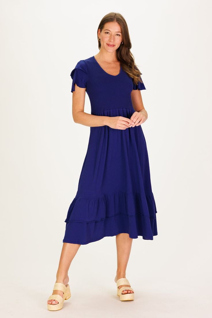 A statement dress that feels as comfortable as loungewear, sign us up! The Mattie Dress is just that and more. The smocking on the chest is so flattering and comfortable that this is going to be our go to dress for everything from vacation to date night. In a classic navy, this piece will last from season-to-season. This dress runs large, we recommend you size down. FAVORITE FEATURES: Smocked Bodice Tiered Flattering V-Neck Ruffle Sleeve Detail Midi Length Solid Color Mid-length Dresses For Vacation, Comfortable V-neck Dress For Spring, Knee-length Midi Dress For Summer Loungewear, Spring Stretch Midi Dress For Loungewear, Casual Maxi Dress With Relaxed Fit For Day Out, Spring Casual Midi Dress For Loungewear, Flowy Casual Dresses For Loungewear, Spring Casual Midi Loungewear Dress, Midi Dress With Smocked Back And Relaxed Fit