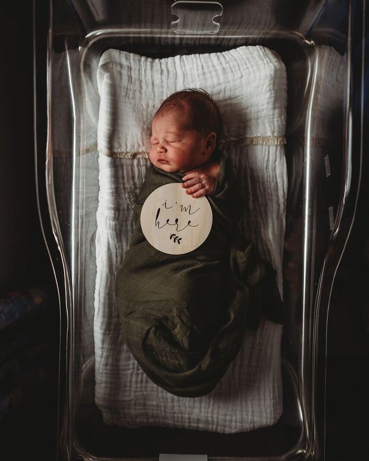 a baby is sleeping in a clear crib with a sign on it's side