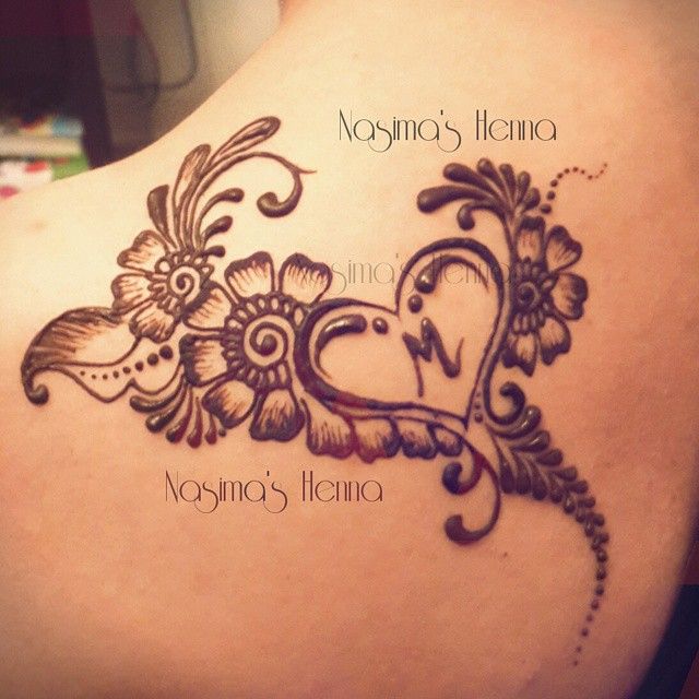 the back of a woman's shoulder with henna tattoos on it and flowers