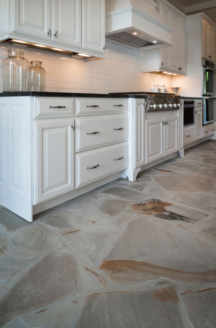 a kitchen with marble floors and white cabinets