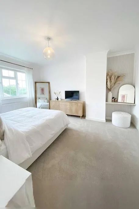 a bedroom with a bed, dresser and television on the far side of the room