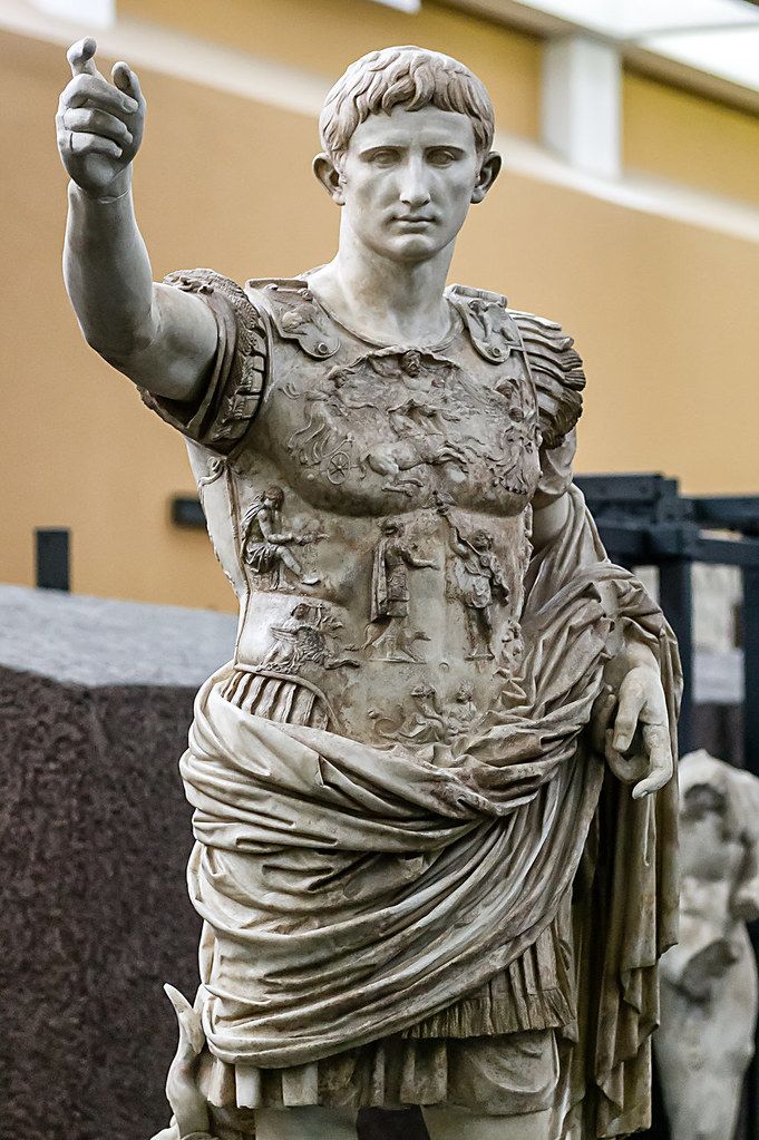 a statue of a man holding his hand up in front of some other statues behind him