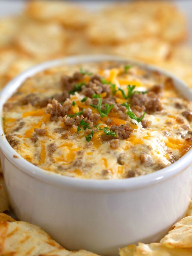 a white bowl filled with cheesy dip surrounded by tortilla chips