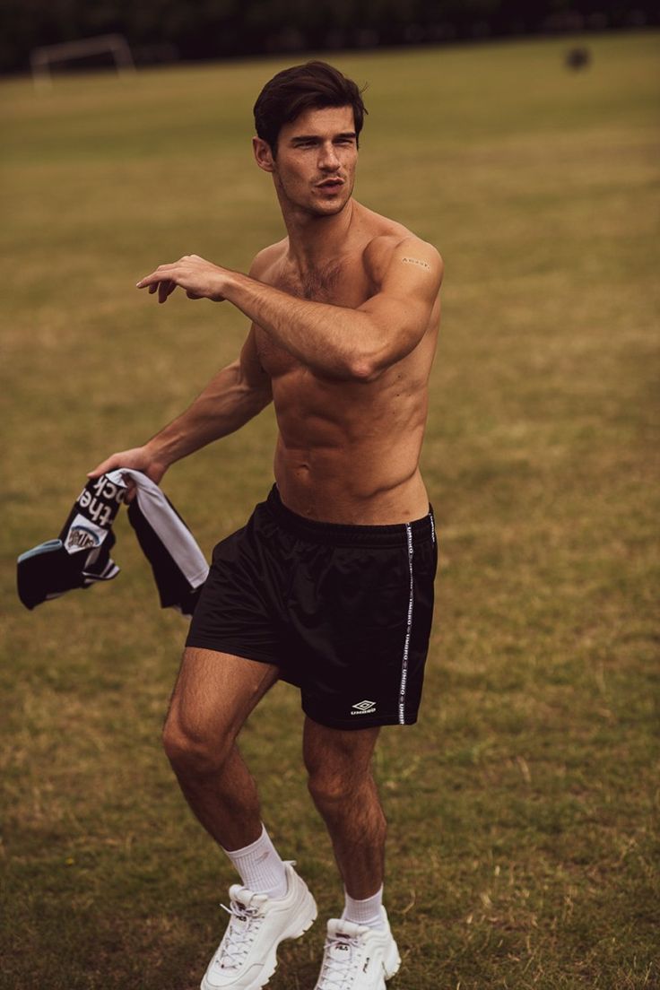 a shirtless man holding a tennis racquet on top of a grass covered field