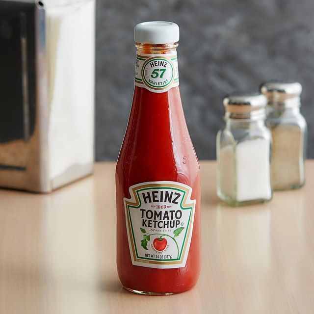 a bottle of heinz's tomato ketchup sitting on a table next to some salt and pepper shakers