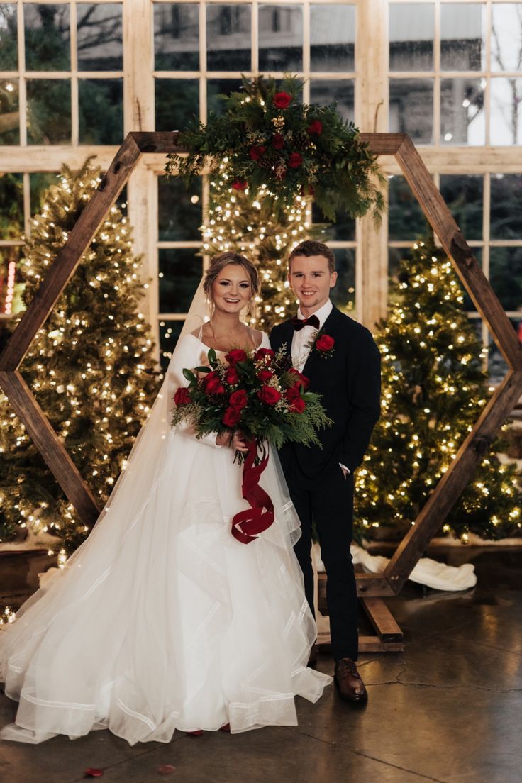 a bride and groom posing for a photo in front of christmas trees at their wedding