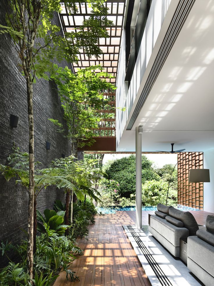 an outdoor living area with wood flooring and plants on either side of the room