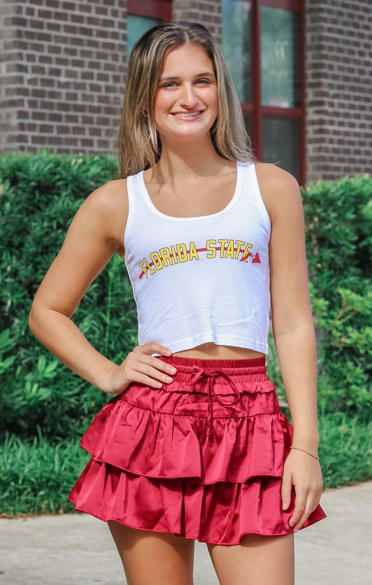 Love a cute, cropped game day tank?! Our "Florida State" Vintage Crop Tank in White is the perfect match for all your fun shorts and skirts. Plus, it's lightweight and breathable, mixed with a super cute retro graphic! Details: *OFFICALLY LICENSED* Super Soft, & Stretchy Tank 50% Cotton, 50% Modal Crew Neckline, No Sleeve, Crop Length Features a Garnet Arrow Graphic under Gold Lettering, Center Chest Color: White True to Size: Relaxed fit Jaden is wearing size Small Garment measurements in inches: Small = Bust: 12 3/4” / Length: 17” Medium = Bust: 13” / Length: 17 3/4” Large = Bust: 13.5” / Length: 17 3/4” X- Large = Bust: 14.5” / Length: 18” Have questions about sizing, fit, or styling? Send us a chat or give us a call at 850-629-4890 during business hours 11AM - 5PM EST Monday-Friday! Casual Tank Top For Game Day In Summer, Casual Summer Tank Top For Game Day, Casual Summer Game Day Crop Top, Casual Summer Crop Top For Game Day, Summer Cheerleading Tops With School Spirit Style, School Spirit Tops For Summer Cheerleading, Summer School Spirit Tops For Cheerleading, Sleeveless Top For Game Day In Spring, Sleeveless Tops For Game Day In Spring