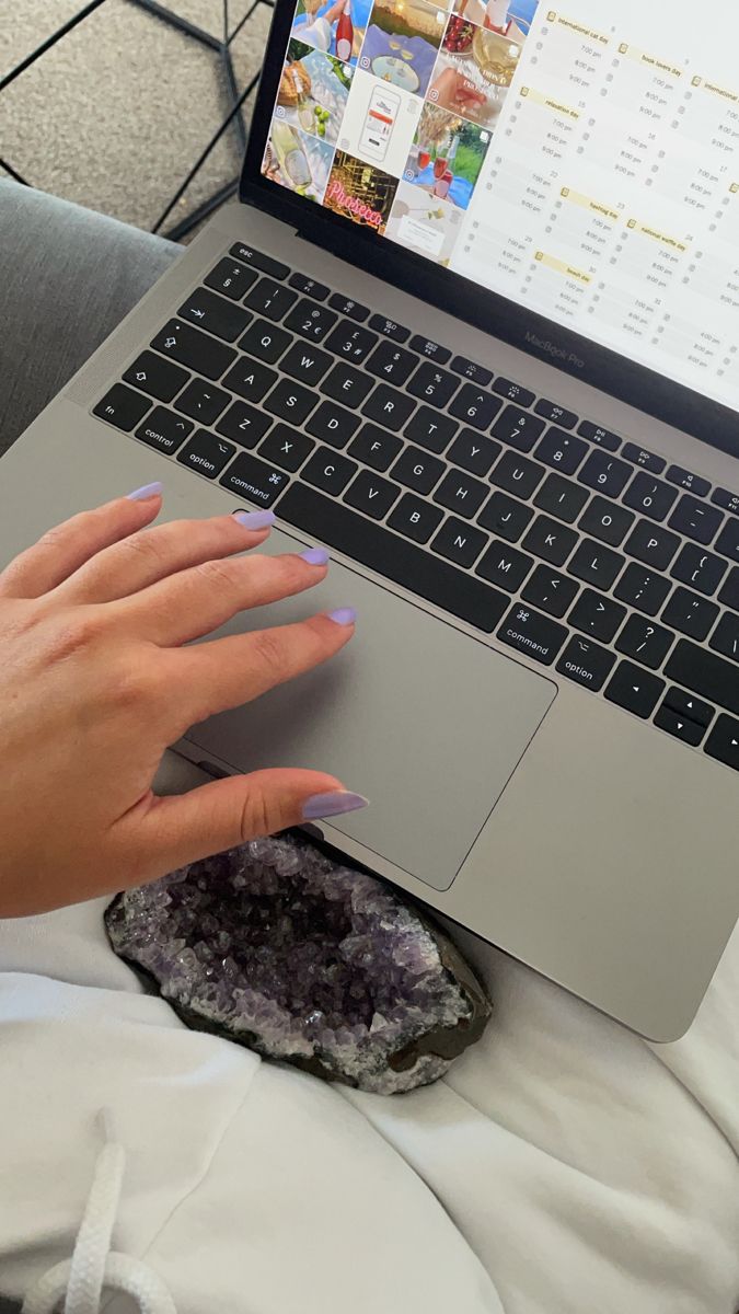 a person using a laptop computer on top of a white blanket with a rock next to it