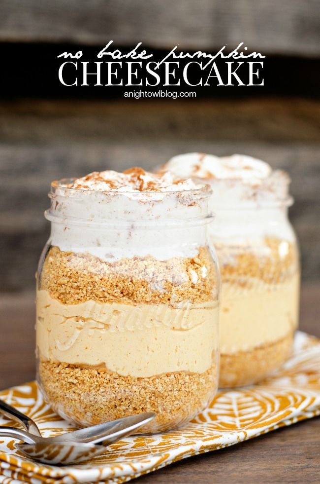 two mason jars filled with dessert sitting on top of a yellow and white napkin next to a fork