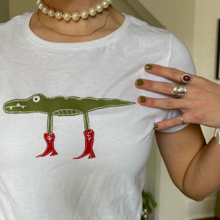 a woman wearing a t - shirt with an alligator on it