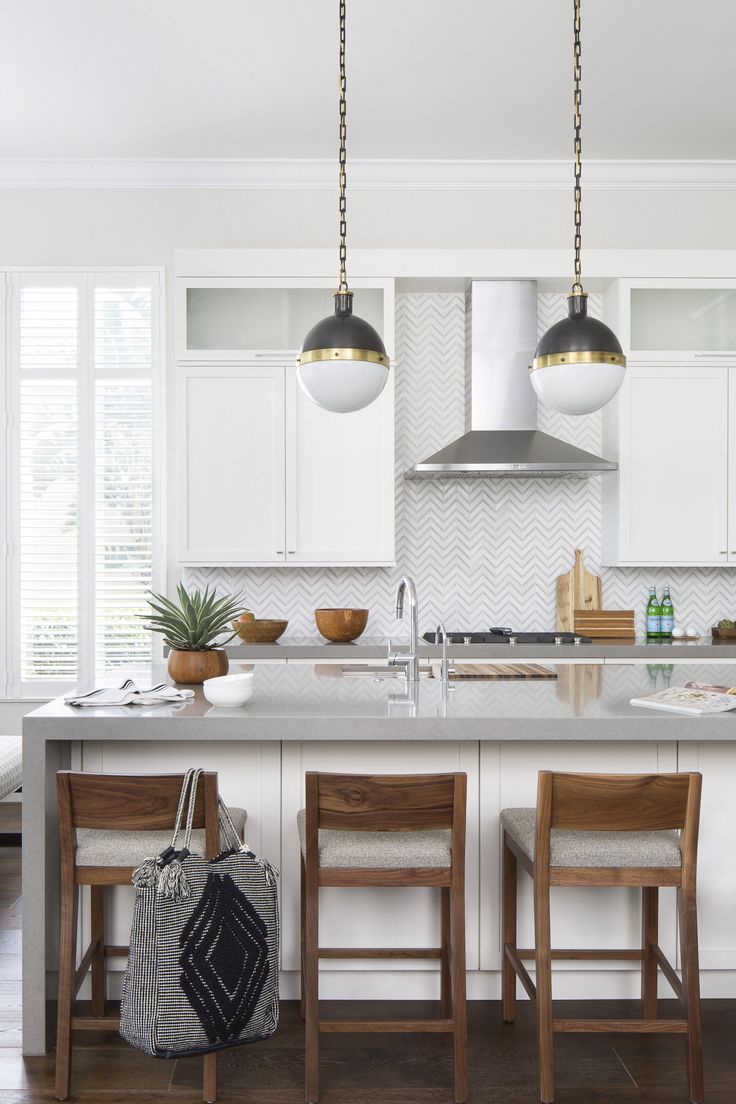 a kitchen with white cabinets and wooden stools next to an island in the middle