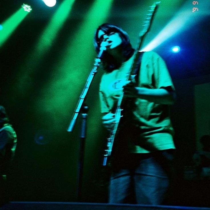 a man standing in front of a microphone on top of a stage with green lights