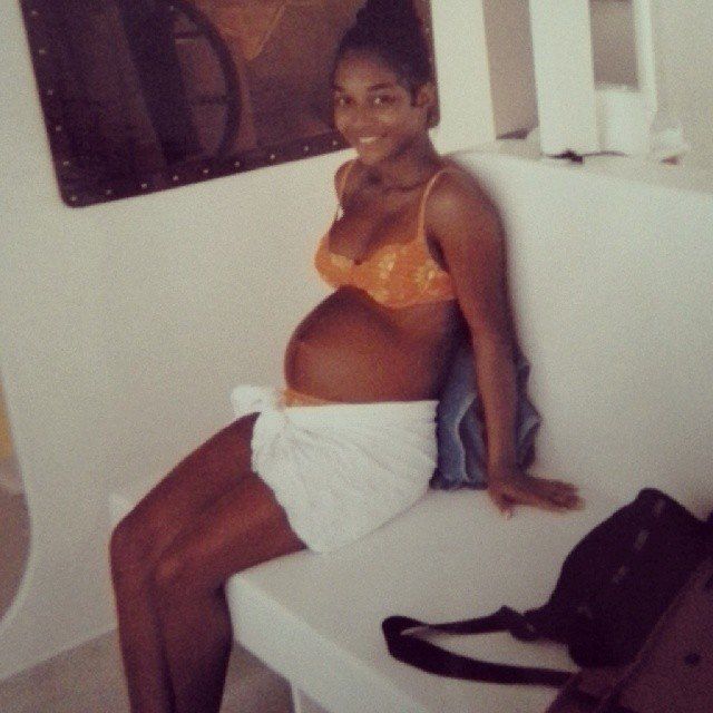 a pregnant woman sitting on top of a white bench