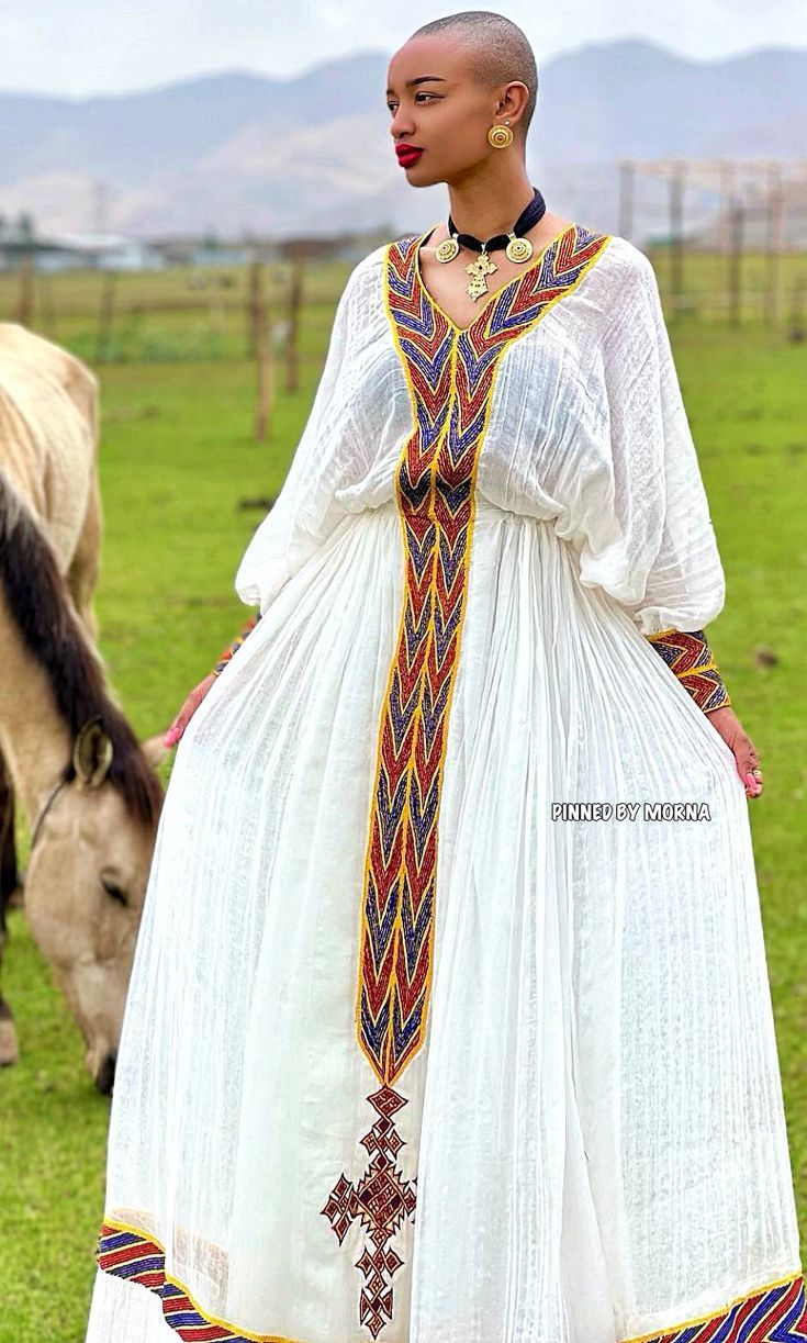 a woman in a white dress standing next to a cow