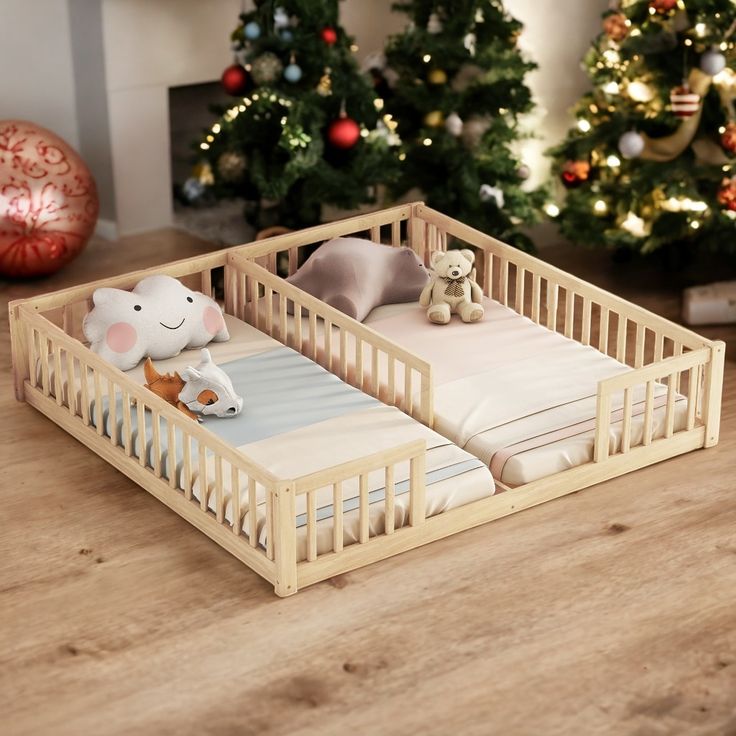 two small wooden cribs with stuffed animals in them on a table next to christmas trees