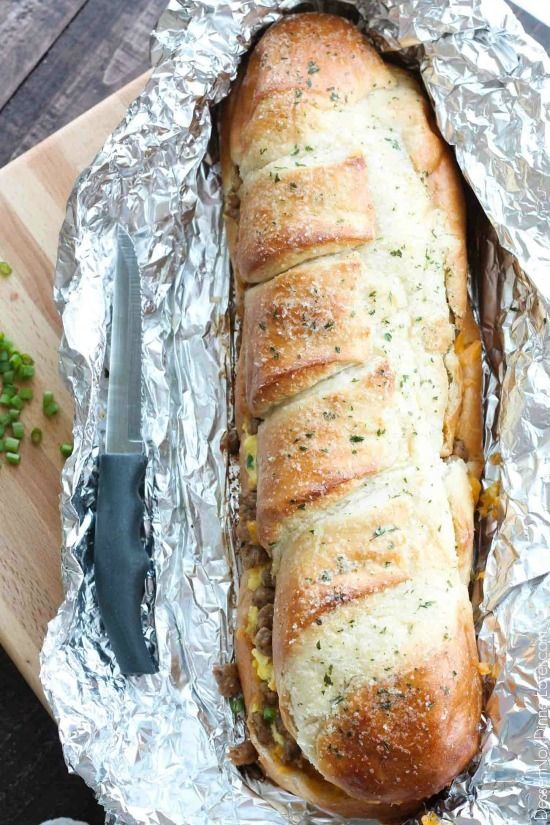 a loaf of bread sitting on top of tin foil covered in seasoning next to a knife