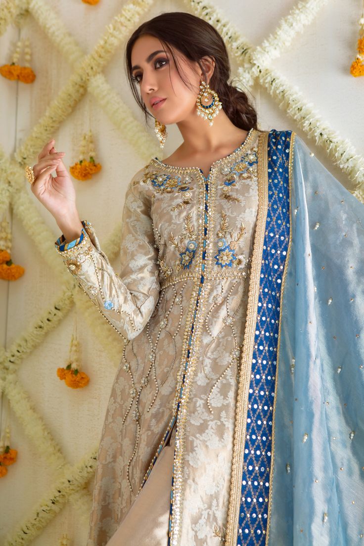 Make a Bold style statement this wedding season with our stunning front open kalidar ensemble, cut from Jacquard soft tissue, featuring contrasting colored-resham floral embroidery accentuated with zardozi, Swarovski, crystals & gota work. Flattering cut, floor length with V-neckline, color-block dhanak pati and gorgeous pearl detailed border adds a festive element to this gorgeous outfit.Paired with tissue staright pants featuring beadwork and stunning kamdani border embellished dupatta with ha Reception Straight Kurta Choli With Dupatta, Festive Resham Embroidered Anarkali Set For Transitional Season, Festive Resham Embroidery Anarkali Set For Transitional Season, Festive Anarkali With Resham Embroidery, Chanderi Sharara For Reception During Eid, Reception Cutdana Chanderi Sharara, Designer Floor-length Chanderi Sharara, Anarkali Sharara With Dabka Work, Chinon Anarkali Set For Reception Navratri