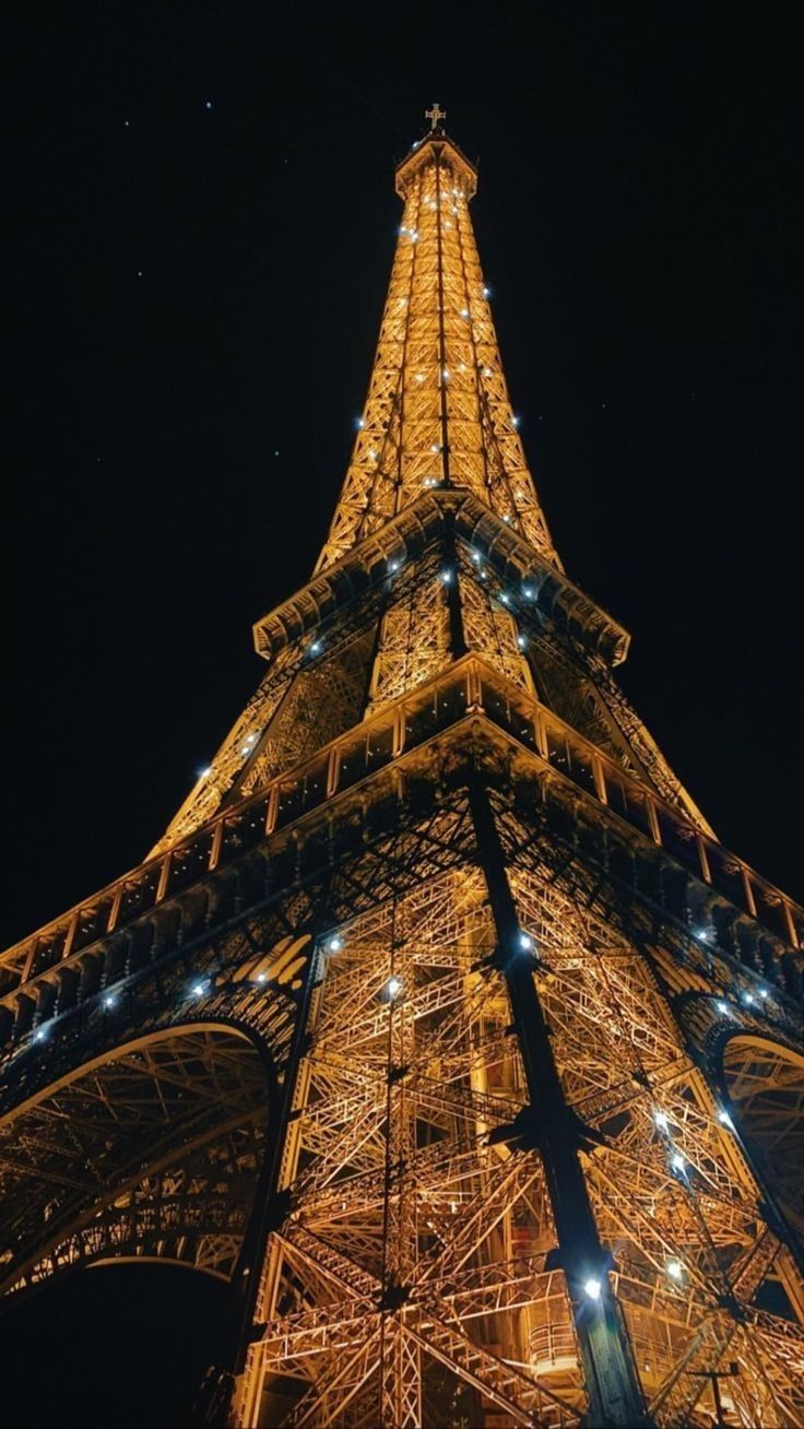 the eiffel tower lit up at night with lights on it's sides