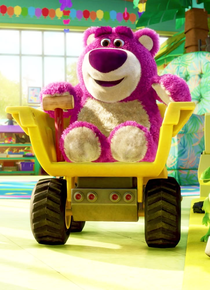 a large pink teddy bear riding on top of a yellow toy truck in a playroom