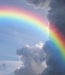 a rainbow in the sky with clouds and water