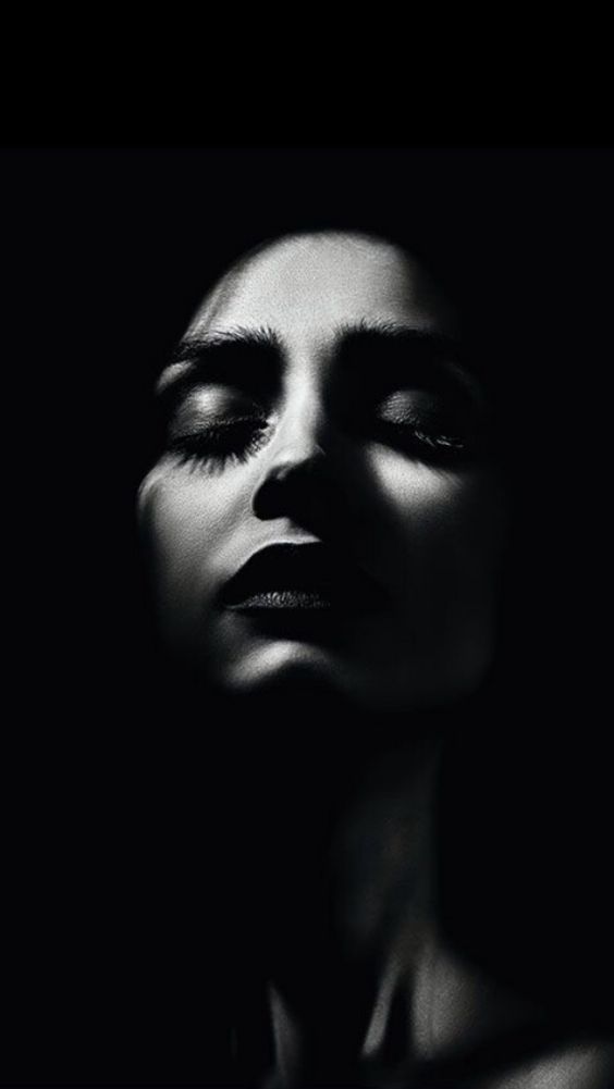 a black and white photo of a woman's face with her eyes closed in the dark