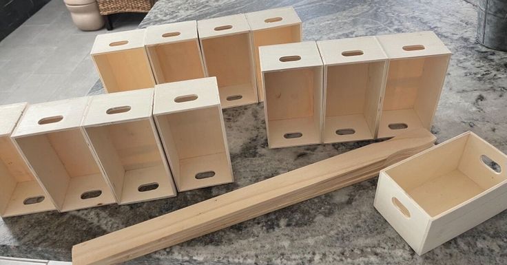 several empty wooden boxes sitting on top of a marble counter next to a planter