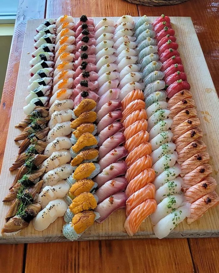 a wooden cutting board topped with lots of different types of sushi