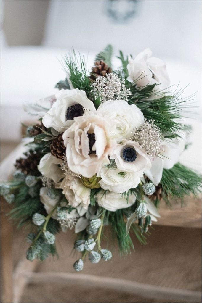 a bridal bouquet with white flowers and pine cones