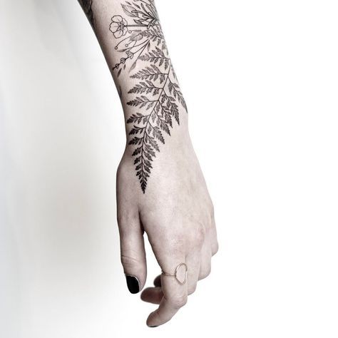 a woman's hand with a black and white tattoo design on her left arm