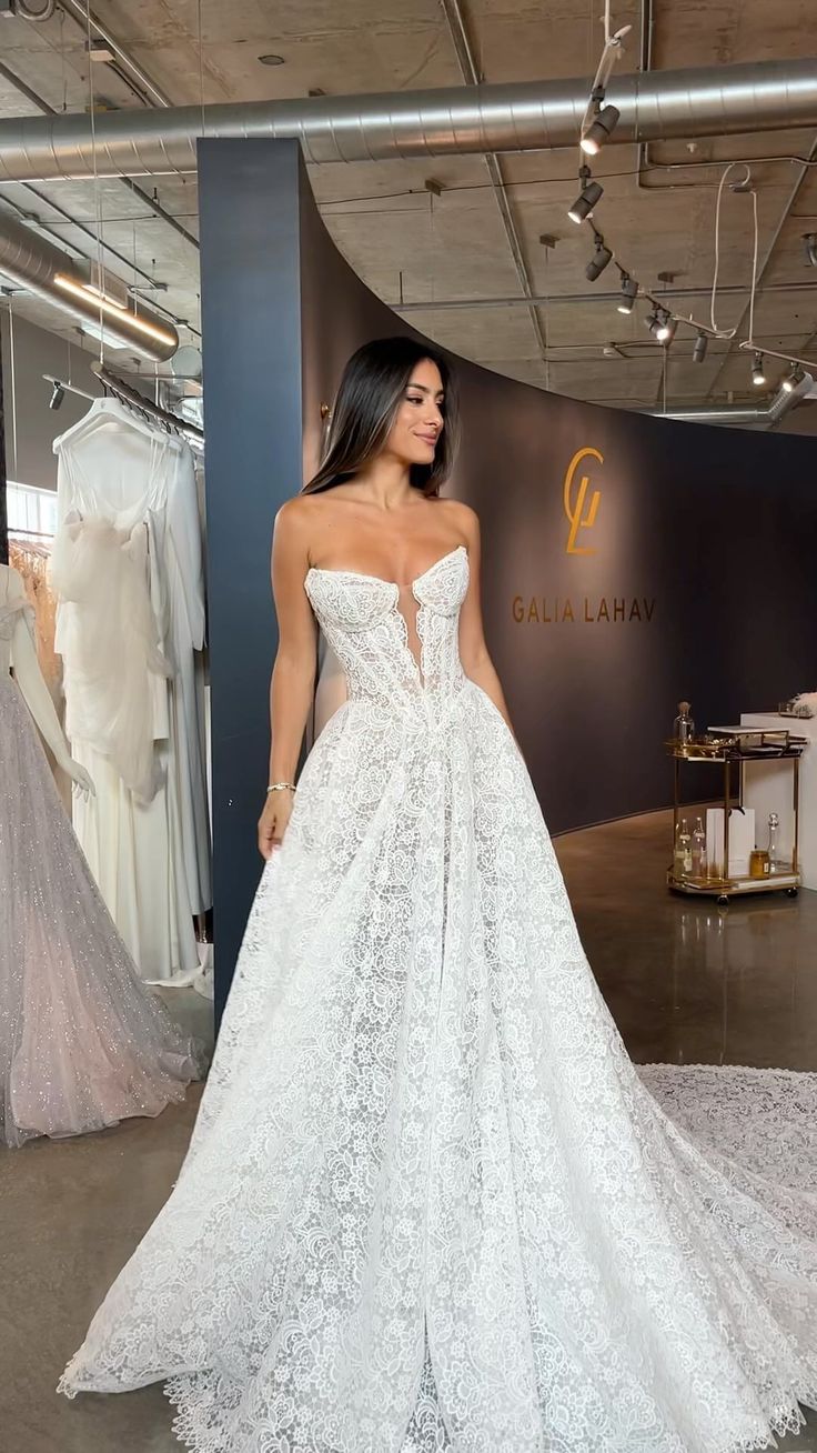 a woman standing in front of a display wearing a wedding dress with an open back