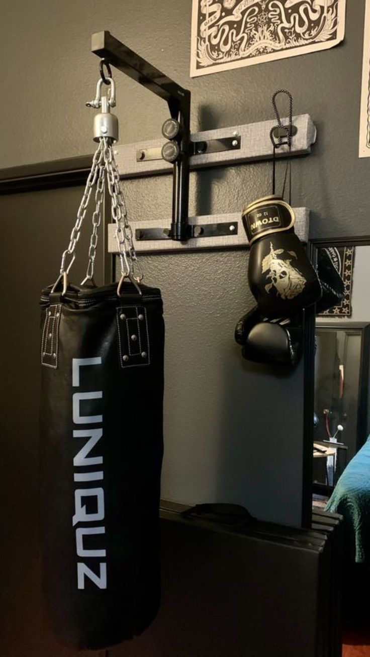 a black boxing bag hanging from the wall next to a pair of punching mitts