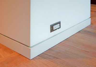 an electrical outlet on the side of a wall in a room with hard wood flooring