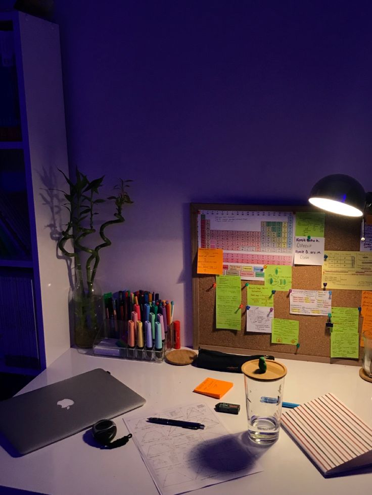 an office desk with sticky notes on the wall and a laptop computer next to it