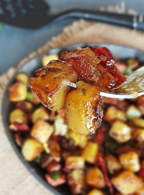 a bowl filled with food sitting on top of a wooden table next to a fork