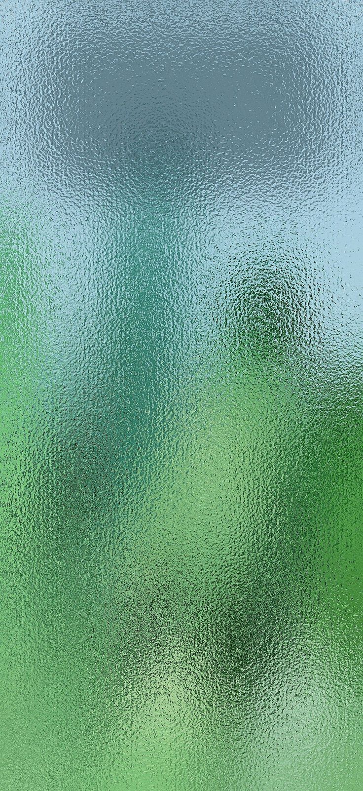 a blurry image of green, blue and white colors on a glass window pane