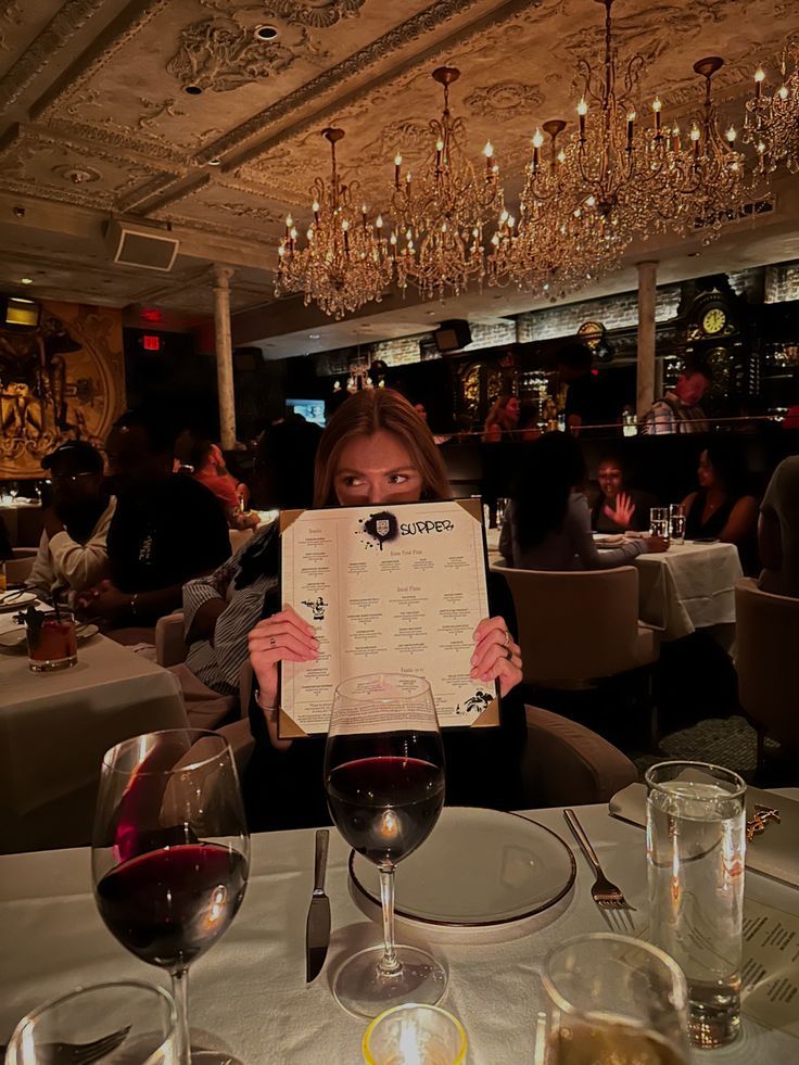 a woman sitting at a table holding up a menu