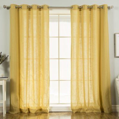 a yellow curtain hanging on the side of a window next to a chair and table