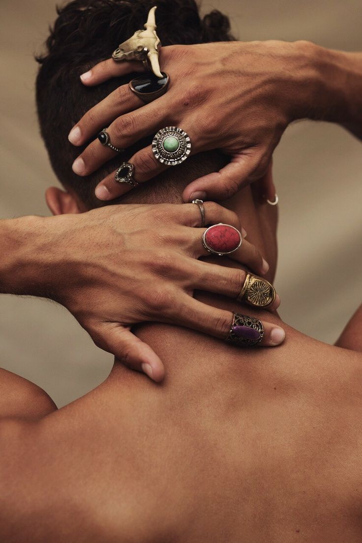 a man with his hands on the back of another mans neck, wearing rings and knick knacks