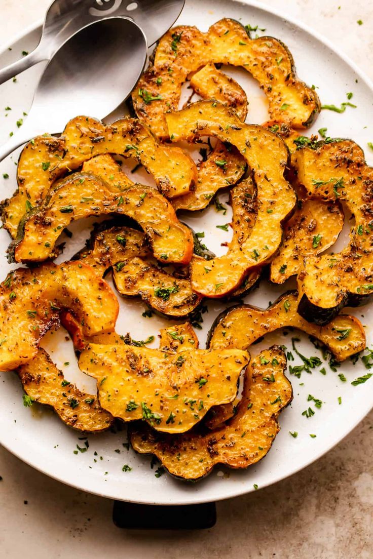 a white plate topped with cooked squash on top of a table next to a fork