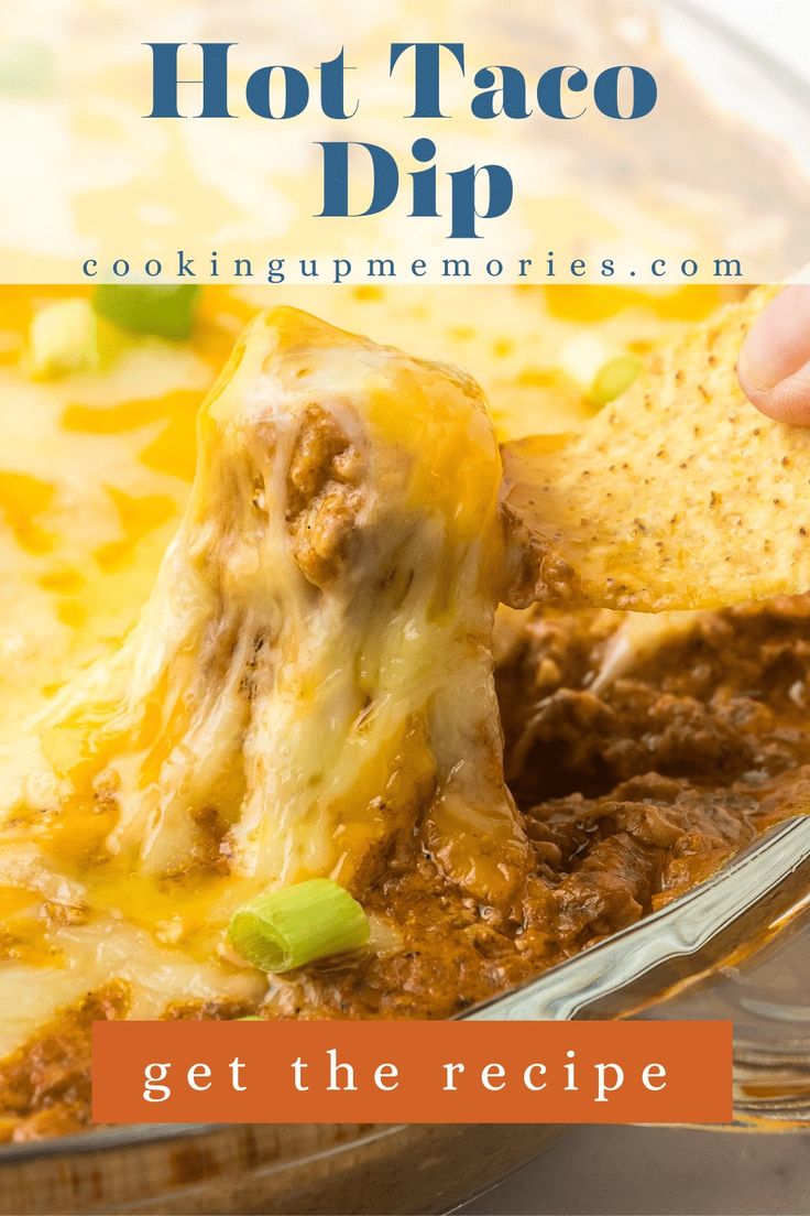 a hand dipping a tortilla chip into a casserole dish