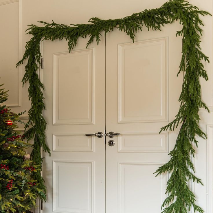 two white doors decorated with christmas greenery