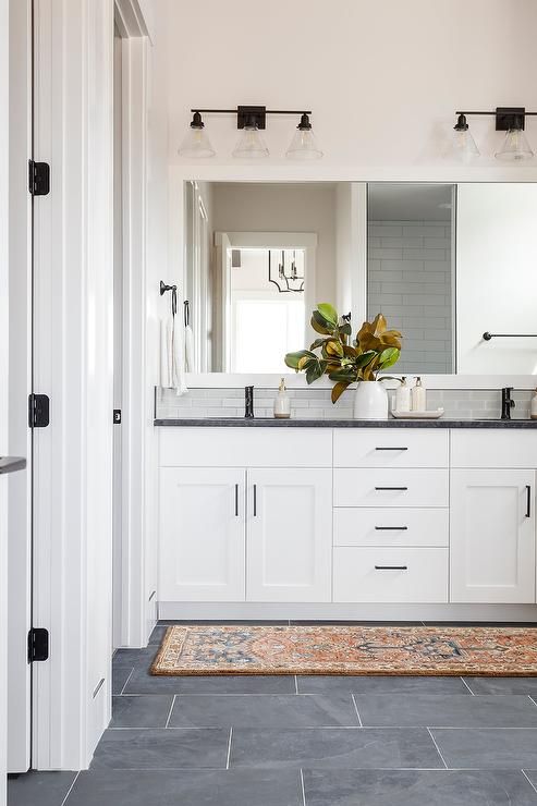 a large bathroom with white cabinets and black counter tops, along with a rug on the floor