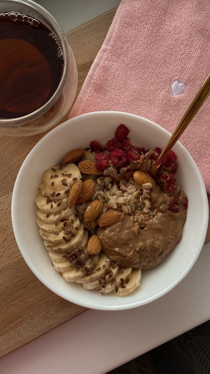 a bowl of oatmeal with bananas, raspberries and almonds