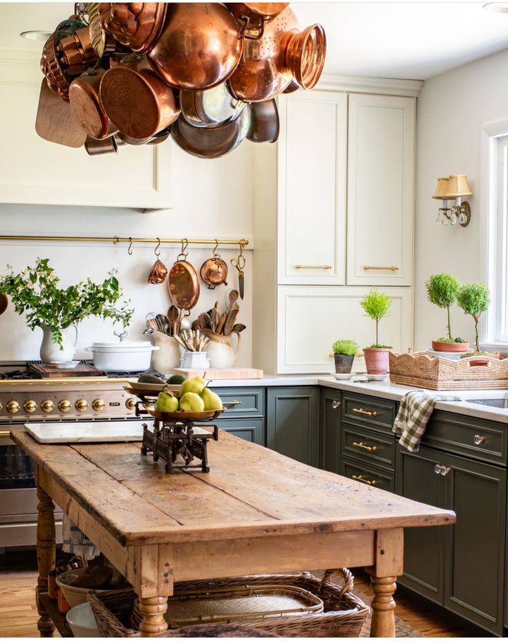 a wooden table in a kitchen with pots and pans hanging from the ceiling above it