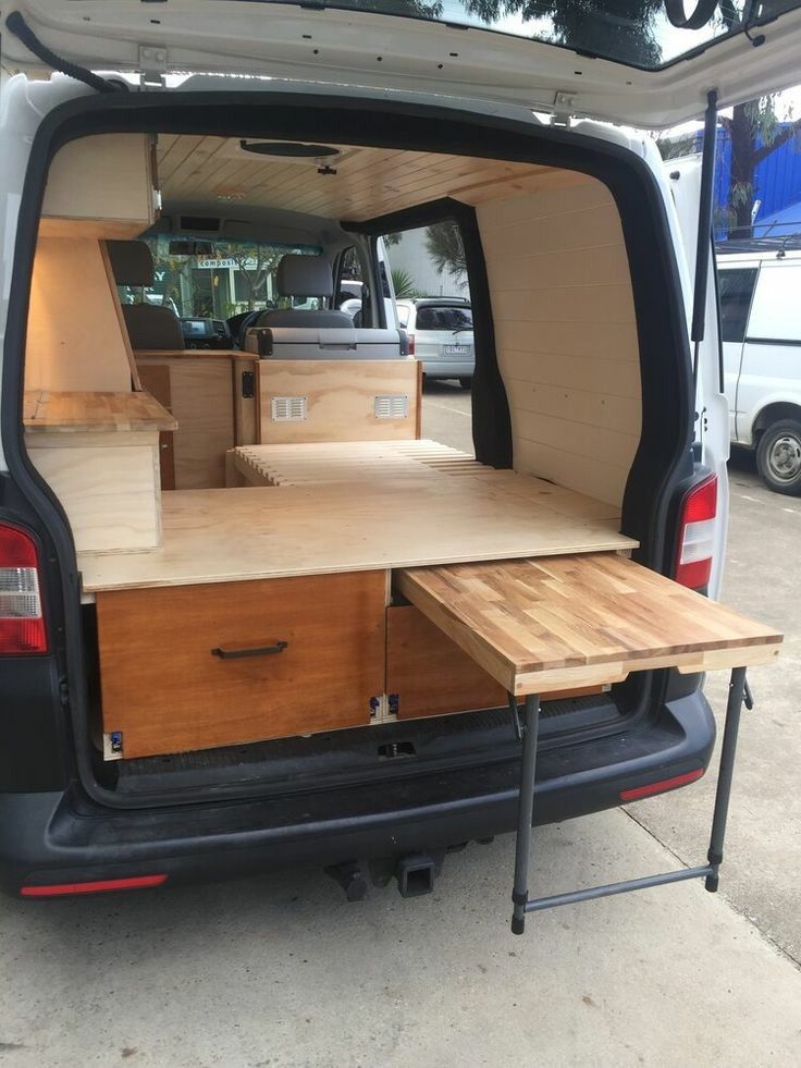 the back end of a van with wooden furniture in it